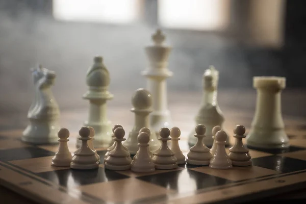 Chess board game concept of business ideas, competition and strategy. Chess figures on a dark background with smoke and fog. Selective focus