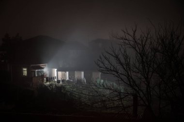 Geceleri ormanda bir hayaletin olduğu eski bir ev ya da sis içinde terk edilmiş bir korku evi. Ölü ağaç ormanındaki eski mistik bina. Geceleri aylı ağaçlar. Gerçeküstü ışıklar. Korku Cadılar Bayramı konsepti