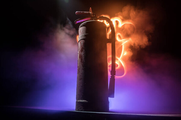 Концепция противопожарной защиты. Старый огнетушитель на темном туманном фоне со светом. Селективный фокус