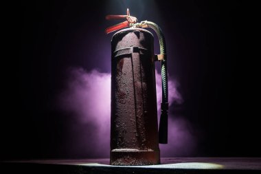 Yangın koruma konsepti. Karanlık sisli arka planda, ışıklı eski bir yangın söndürücü. Seçici odak