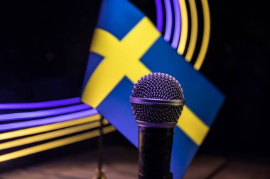 Yakın plan İsveç 'te bulanık bir bayrağın arka planındaki mikrofon. Karanlık masa dekorasyonu. Seçici odak