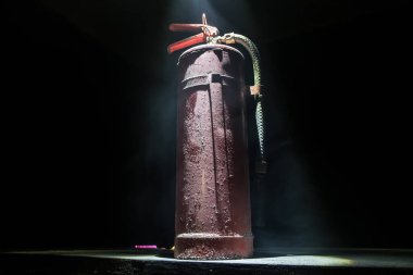 Yangın koruma konsepti. Karanlık sisli arka planda, ışıklı eski bir yangın söndürücü. Seçici odak