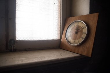 Time concept. Old rustic wall clock on grunge dirty windowsill. Studio shot.