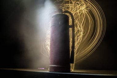 Yangın koruma konsepti. Karanlık sisli arka planda, ışıklı eski bir yangın söndürücü. Seçici odak