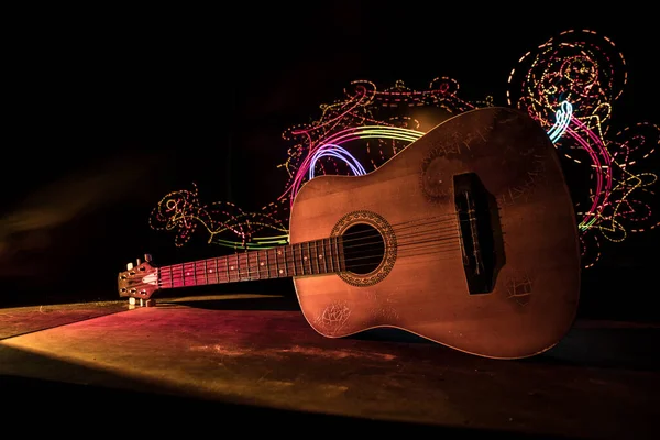Music concept. Acoustic guitar isolated on a dark background under beam of light with smoke with copy space. Guitar Strings, close up. Selective focus.