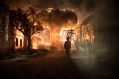 Resim dekorasyon. Bir adam bir yolda ayakta şehri yaktı. Kıyamet kenti Afet film poster kavram olarak şehir merkezinde. Gece sahne. Şehir savaşta yok. Seçici odak