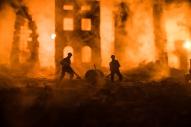 War Concept. Military silhouettes fighting scene on war fog sky background. Sappers clears mines at the site of recent fighting zone. Battle in ruined city. Selective focus