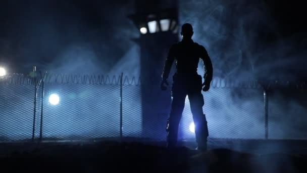 刑事司法収容の概念や刑務所破壊の概念 夜に監視塔と共に刑務所の塀の近くに立っている囚人のシルエット クリエイティブアートデコレーション 選択的なフォーカス — ストック動画