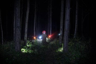 Geceleri ormanda kirli bir kostüm giyen korkunç kötü bir palyaço. Gece ormanı, korku Cadılar Bayramı konsepti