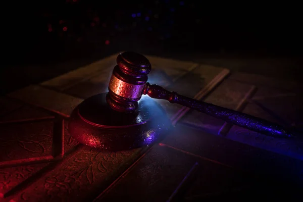 Law theme, mallet of the judge on wooden desk. Law gavel on dark foggy background with light. Selective focus