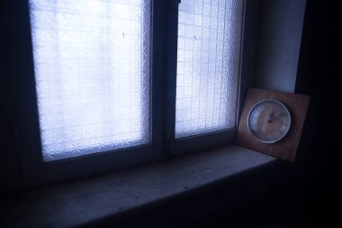 Time concept. Old rustic wall clock on grunge dirty windowsill. Studio shot.