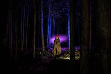 Geceleri ormanda kirli bir kostüm giyen korkunç kötü bir palyaço. Gece ormanı, korku Cadılar Bayramı konsepti