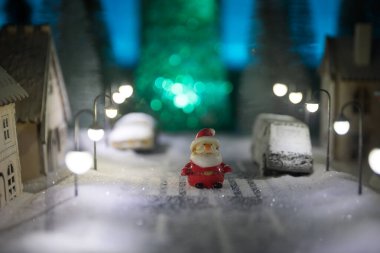 Kışın karlı küçük dekoratif evler, Noel ve yeni yıl minyatür evleri geceleri karlı köknar ağaçları. Tatil konsepti. Seçici odak