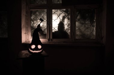 Geceleri mistik evdeki korkunç Cadılar Bayramı balkabağı ya da penceredeki cadılar bayramı balkabağı ve korku silueti. Seçici odak