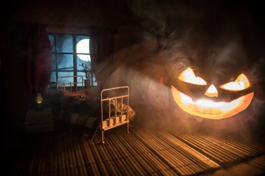 Korku Cadılar Bayramı konsepti. Geceleri mobilyaları ve pencereleri olan gerçekçi bir bebek odası. Dev bir balkabağıyla yatakta korkmuş bir adam. Seçici odak