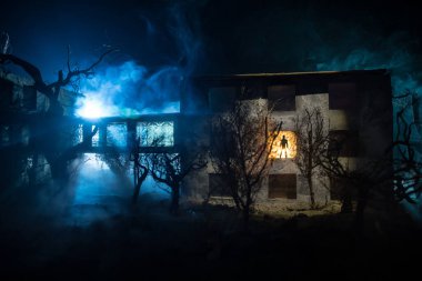 Karanlık ormanda ışıkla duran bir insan silueti. Korku Cadılar Bayramı konsepti. Terk edilmiş binada garip bir siluet.