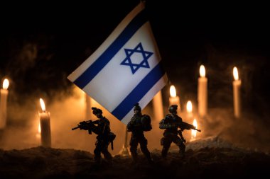 Israel flag on burning dark background with candle. Attack on Israel, mourning for victims concept or Concept of crisis of war and political conflict. Selective focus clipart