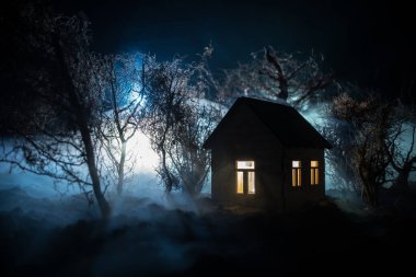 Karanlık ormanda ışıkla duran bir insan silueti. Korku Cadılar Bayramı konsepti. Karanlık ve ürkütücü bir köyde tuhaf bir siluet.