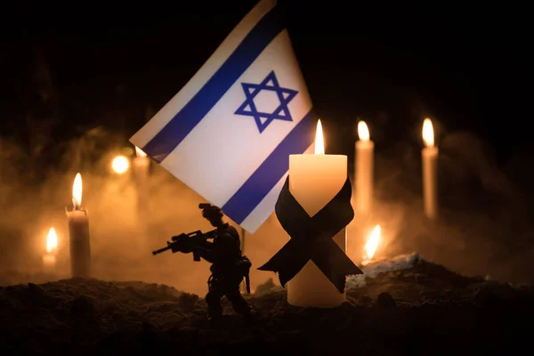 Israel flag on burning dark background with candle. Attack on Israel, mourning for victims concept or Concept of crisis of war and political conflict. Selective focus
