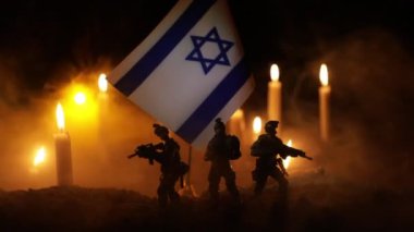 İsrail bayrağı yanan karanlık arka planda mumlarla. İsrail 'e saldırı, mağdur konsepti veya savaş krizi ve siyasi çatışma konsepti için yas tutma. Seçici odak.