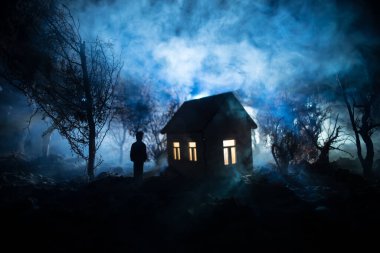 Karanlık ormanda ışıkla duran bir insan silueti. Korku Cadılar Bayramı konsepti. Karanlık ve ürkütücü bir köyde tuhaf bir siluet.