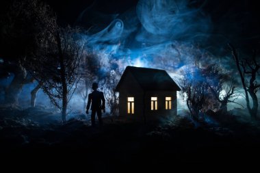 Karanlık ormanda ışıkla duran bir insan silueti. Korku Cadılar Bayramı konsepti. Karanlık ve ürkütücü bir köyde tuhaf bir siluet.