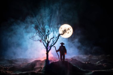 Karanlık ormanda ışıkla duran bir insan silueti. Korku Cadılar Bayramı konsepti. Karanlık ve ürkütücü bir köyde tuhaf bir siluet.
