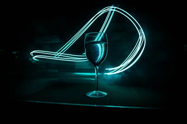 Wine glass on dark bar background low light. Colorful wine glasses with light on backside in selective focus