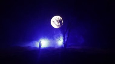 Karanlık ormanda ışıkla duran bir insan silueti. Korku Cadılar Bayramı konsepti. Karanlık ve ürkütücü bir köyde tuhaf bir siluet.