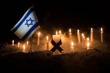 Israel flag on burning dark background with candle. Attack on Israel, mourning for victims concept or Concept of crisis of war and political conflict. Selective focus clipart