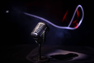 Ses, müzik için mikrofon, ses stüdyosunda ya da sahnede karaoke. Mikrofon teknolojisi. Konuşma yayın ekipmanı. Karanlık odadaki mikrofon, arka farlı masanın üstünde. Seçici odak