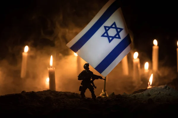 Israel flag on burning dark background with candle. Attack on Israel, mourning for victims concept or Concept of crisis of war and political conflict. Selective focus