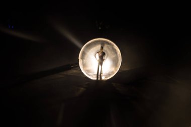 Karanlık arka planda, taş yüzeyde büyüteç, aydınlık altında, gizemli dedektif konsepti. Dev büyüteçin yanında duran bir kişinin silueti.