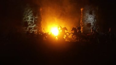 Süvari ve piyadelerle ortaçağ savaş sahnesi. Şekillerin siluetleri ayrı nesneler olarak, karanlık tonlu sisli arka planda ortaçağ şatosuyla savaşan savaşçılar arasında. Seçici odak