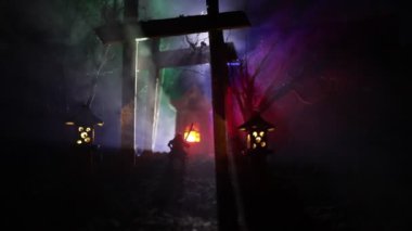 Karanlık ormanda ışık altında duran heykelciklerden oluşan bir siluet. Korku cadılar bayramı konsepti, karanlık ürkütücü köyde garip siluetler.