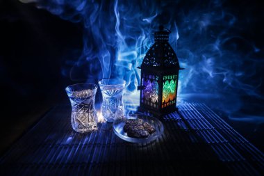 Ramazan orucu sırasında Suhoor veya iftar zamanı. Bir bardak su ve oruç tutmak için hurma. Kutlama kartı, Müslüman kutsal ayı için davetiye Ramazan Kareem. Seçici odak