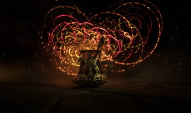 Arap çayı bardakta, doğu aperatifleriyle birlikte koyu arkaplanda, ışık ve dumanlı taş bir zemin üzerinde. Doğu çay konsepti. Seçici odak.