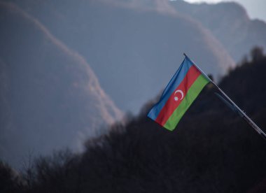 Azerbaycan bayrağı, dağda dalgalanan bayrak. Azerbaycan 'ın ulusal bayrağı güneşli bir günde güçlü bir rüzgarda. Açık hava doğa çekimi.