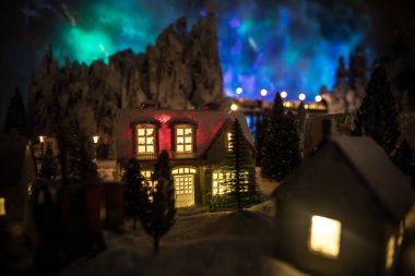 Kışın karlı küçük dekoratif evler, Noel ve yeni yıl minyatür evleri geceleri karlı köknar ağaçları. Tatil konsepti. Seçici odak