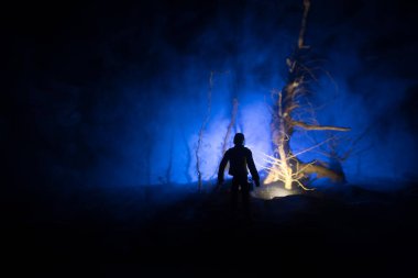 Karanlık ormanda duran bir insan silueti. Korku Cadılar Bayramı konsepti. Gecenin karanlığında ürkütücü bir ormanda tuhaf bir siluet.