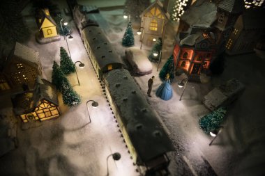 Noel evleri, tren istasyonları, ağaçlarla kaplı kış manzaralarının minyatürü. Gece sahnesi. Eski oyuncak şehrinde yeni yıl. Seçici odak