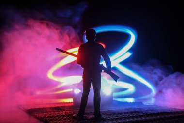 Bir av partisi sırasında tüfekli bir adamın silueti ava nişan alıyor. Renkli sisli arka planda minyatür siluet. Seçici odak