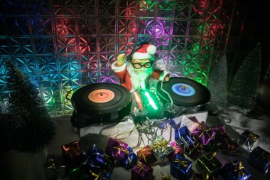 Noel ve Yeni Yıl Kulübü konsepti. Kulaklıklı DJ mixerı. Noel Baba pikapta karışıyor. Kar üzerine yaratıcı minyatür sanat dekorasyonu.