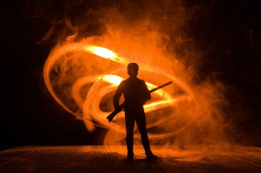 Bir av partisi sırasında tüfekli bir adamın silueti ava nişan alıyor. Renkli sisli arka planda minyatür siluet. Seçici odak