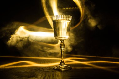 Koyu barın arka planında şarap kadehi düşük ışık. Arkasında ışık olan renkli şarap kadehleri seçici odak noktasında