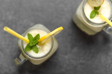 Saman dolu cam kavanozlarda iki limonata. Karanlık arka planda taze yaz içkileri.