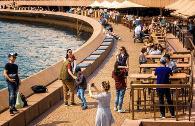 Sydney, NSW, Avustralya, 5 Şubat 2020 Sydney Opera Binası 'nın önündeki Waterside restoranında arka planda Sydney silüeti olan insanlar.