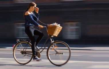 Kopenhag 'ın merkezinde bisikletli genç bir kadın güneşli bir öğleden sonra Danimarka' da