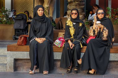Üç üst sınıf Arap, Burç Kalifa, Dubai yakınlarındaki bir bankta dinleniyor.