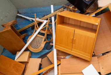 Masalar, sandalyeler ve diğer ev eşyaları da dahil olmak üzere eskimiş mobilyalar, bir geri dönüşüm istasyonunda büyük bir metal konteynıra atılarak uygun atık bertaraf ve çevresel sürdürülebilirliği teşvik ediliyor..